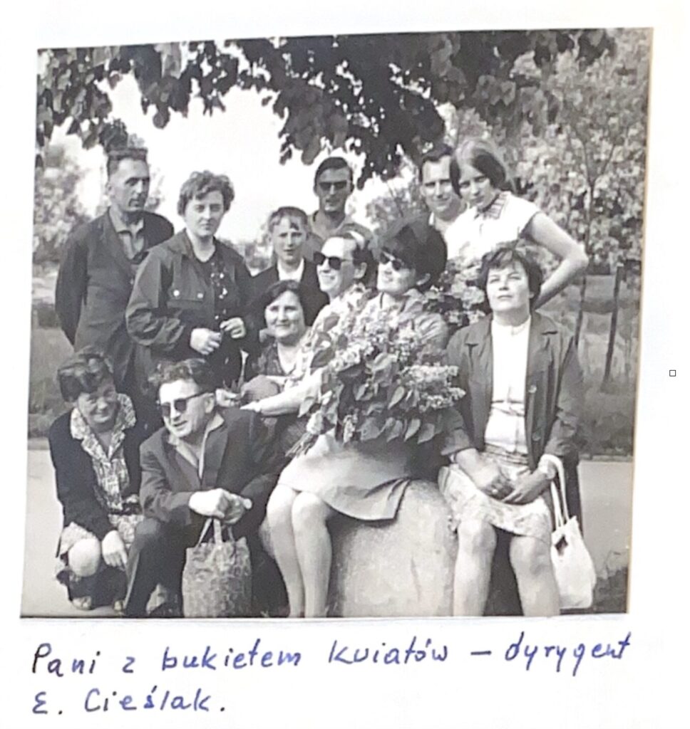 Fotografia z kroniki Chóru przedstawiająca chórzystów z dyrygentką E. Cieślak